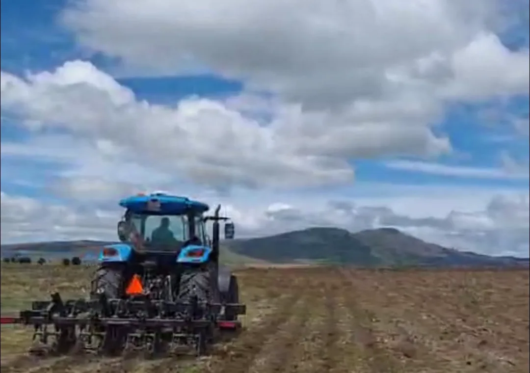Tractor working a field with mountains behind